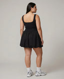 Model facing away showing the back of the black balloon mini dress in a studio setting.