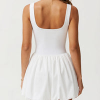 Ghost mannequin back view of white balloon hem active dress displaying racerback detail and gathered skirt.
