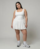 Model wearing white balloon hem active dress in a front-facing studio shot with sneakers and headband.