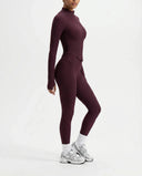 Plus size model front view wearing the wine red zip-up jacket top styled with matching high waist leggings.