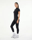 Woman wearing brown jumpsuit legging walking outdoors in natural light with white sneakers and relaxed styling.