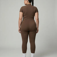 Female model rear studio view wearing black full-length activewear jumpsuit showing back silhouette and seamless construction.
