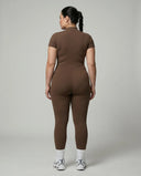 Female model rear studio view wearing black full-length activewear jumpsuit showing back silhouette and seamless construction.