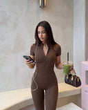 Plus size model back view wearing black compression activewear jumpsuit showing inclusive fit and clean lines.