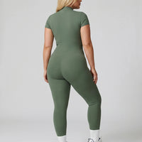 Female model from behind wearing green ribbed half-zip jumpsuit showing back fit in studio setting.