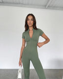 Plus size model from behind wearing green ribbed half-zip jumpsuit showing full-body fit.