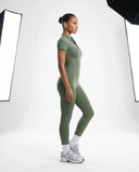 Woman wearing green ribbed jumpsuit walking outdoors in casual athleisure lifestyle setting.