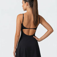 Back view of women's black padel dress with built-in compression shorts on ghost mannequin showing strap detail and clean finish.