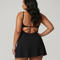 Back view of model wearing black padel dress with built-in shorts in studio showing clean back design and flattering silhouette.