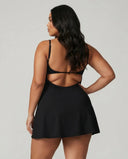 Back view of model wearing black padel dress with built-in shorts in studio showing clean back design and flattering silhouette.
