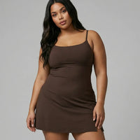 Model wearing brown sculpting padel dress with sneakers in front-facing studio shot.