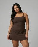 Model wearing brown sculpting padel dress with sneakers in front-facing studio shot.