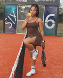 Back view of plus size model wearing brown athletic padel dress in studio.