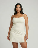 Model wearing the SEEN Essential creme padel dress with side slit detail, front studio view paired with white sneakers.