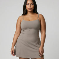 Model wearing grey padel dress with built-in support and flared skirt, front studio view.
