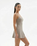 Model styling grey padel dress with sneakers in an active lifestyle setting.