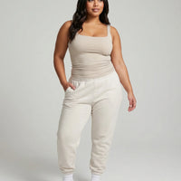 Model wearing beige square neck sleeveless tank top, front studio shot with neutral background.