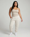 Model wearing beige square neck sleeveless tank top, front studio shot with neutral background.