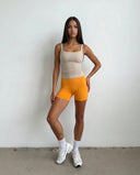 Plus size model wearing beige sleeveless tank top, back view showing strap placement and fit.