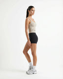 Woman in beige sleeveless tank top styled with neutral joggers in relaxed lifestyle setting.