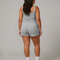 Female model rear studio shot wearing gray sleeveless crop tank showing back fit and strap width.