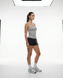 Lifestyle shot of woman wearing gray sleeveless tank top mid-movement during a gym workout session.