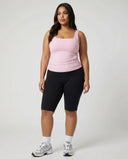Female model facing forward in a studio wearing a pink square neck sleeveless tank top with black leggings.