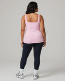Female model from behind in a studio wearing a pink sleeveless activewear tank top.