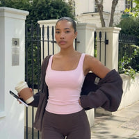 Plus size model front view wearing a pink sculpting sleeveless tank top paired with dark leggings.