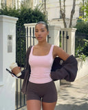 Plus size model front view wearing a pink sculpting sleeveless tank top paired with dark leggings.