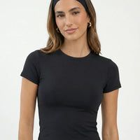 Ghost mannequin back view of the black fitted t-shirt top displaying smooth seam construction and tapered hem.