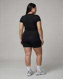 Female model facing away in a studio showing the back fit of the black short sleeve t-shirt top.