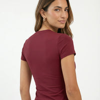 Ghost mannequin back view of red crew neck t-shirt top displaying smooth seam construction.