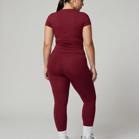 Female model facing away in studio showing the back fit of the red sculpting t-shirt top.