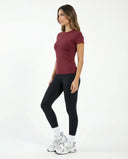 Lifestyle shot of woman in red crew neck gym tee mid-workout in a bright studio setting.