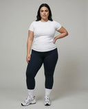 Female model facing forward in studio wearing white ribbed compression t-shirt top with high waist bottoms.