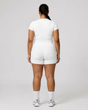 Female model from behind in studio showing the back fit of white ribbed crew neck tee.