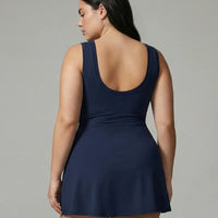 Model wearing blue active dress with wrap skirt tie detail, back view in studio showcasing the fitted bodice and skirt drape.