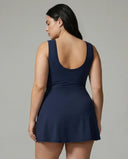 Model wearing blue active dress with wrap skirt tie detail, back view in studio showcasing the fitted bodice and skirt drape.