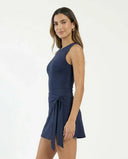 Woman wearing blue active dress with wrap skirt detail in a lifestyle setting, styled for casual athleisure wear.