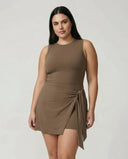 Model wearing brown active dress with wrap skirt detail, front studio view showing fitted silhouette and tie detail at waist.