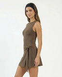 Model styling brown active dress with wrap skirt detail in lifestyle setting, paired with sneakers for an effortless athleisure look.