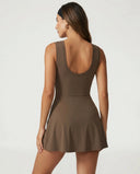 Women's brown active dress with wrap skirt detail displayed on ghost mannequin, back view highlighting sleeveless design and clean finish.