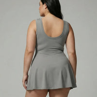 Model wearing grey active set featuring sleeveless top and wrap skirt, rear studio view showing smooth back silhouette.