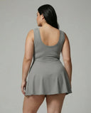 Model wearing grey active set featuring sleeveless top and wrap skirt, rear studio view showing smooth back silhouette.