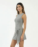 Woman styled in grey active set with wrap skirt walking outdoors in an athleisure lifestyle setting.