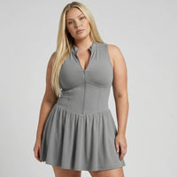 Model wearing SEEN Essential grey padel dress in front-facing studio shot with New Balance sneakers and white socks.