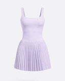 Lifestyle shot of woman in the SEEN Essential purple pleated tennis dress mid-movement highlighting skirt flow and active versatility.