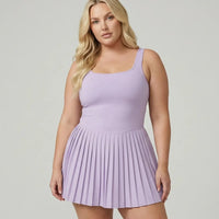 Lifestyle shot of woman in the SEEN Essential purple pleated tennis dress mid-movement highlighting skirt flow and active versatility.