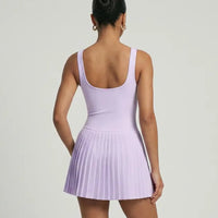 Lifestyle shot of woman in the SEEN Essential purple pleated tennis dress mid-movement highlighting skirt flow and active versatility.